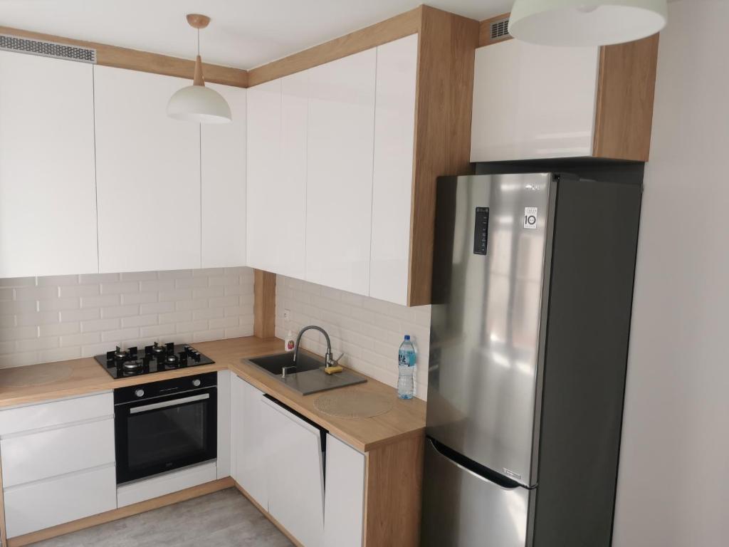 a kitchen with white cabinets and a stainless steel refrigerator at Town Square Apartment in Lublin