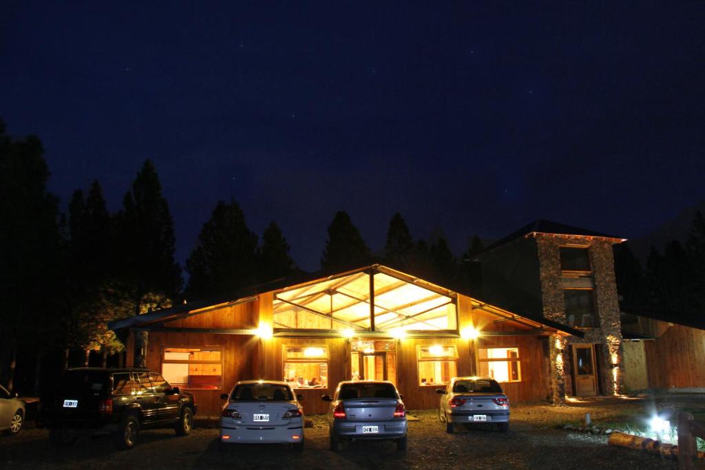 un gruppo di auto parcheggiate di fronte a un edificio di notte di Paralelo 42° Lodge a El Maitén