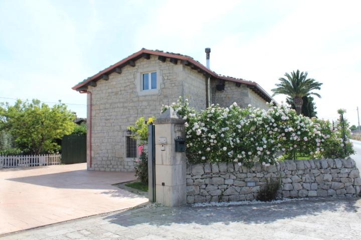 a small house with a stone wall with flowers at Appartamento Le Tre Palme in Frigintini