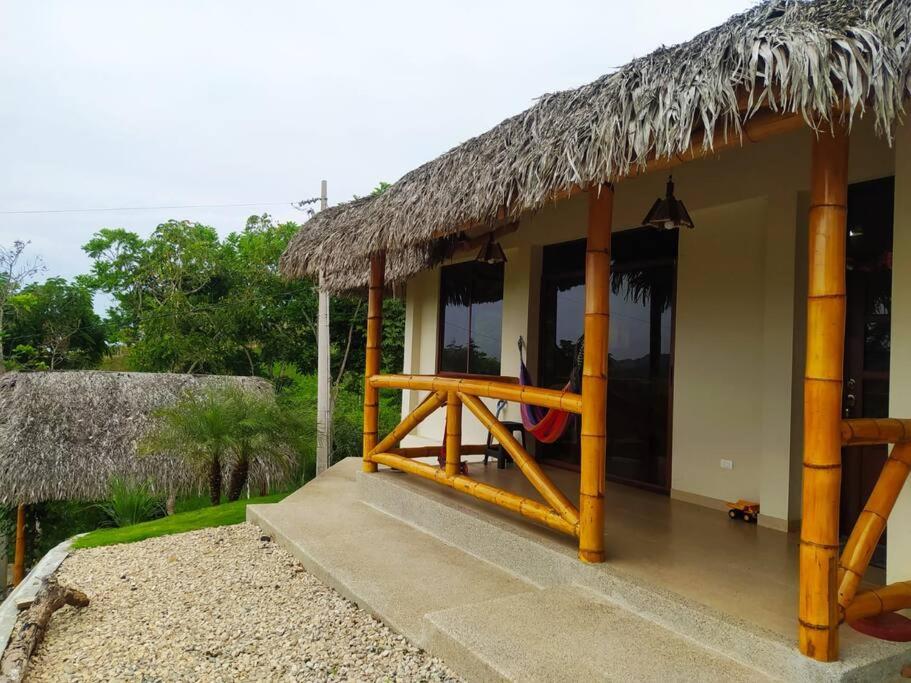 une maison avec un toit de chaume et une terrasse couverte dans l'établissement Agradable casa de campo con estacionamiento, à Olón