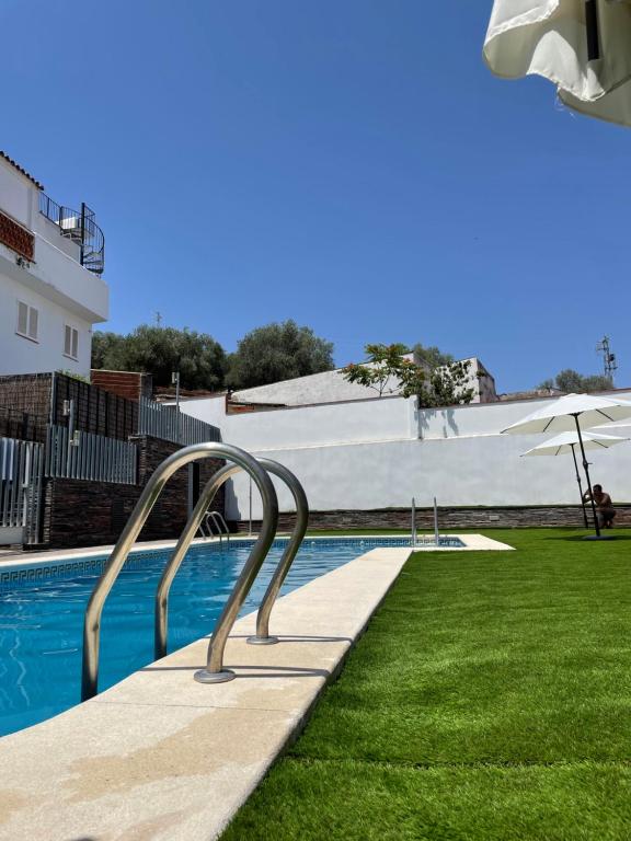 a pool with green grass and a white building at La Cultureta in Segura de León