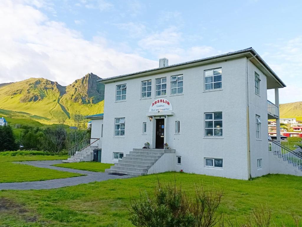 a white building with stairs and mountains in the background at Arsalir Guesthouse Vik B&B in Vík