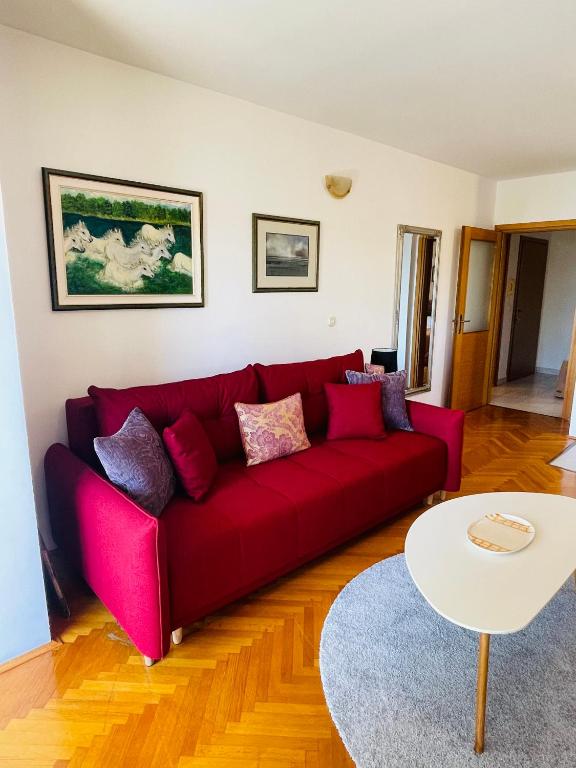 un sofá rojo en una sala de estar con mesa en Peace Sea View Apartment, en Makarska