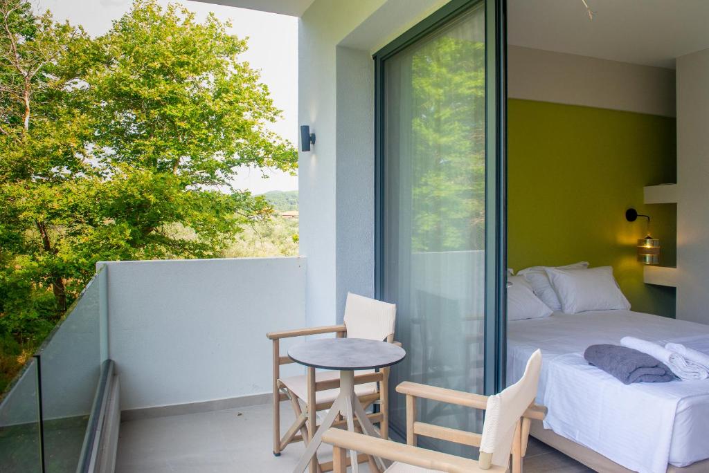 Un dormitorio con una cama y una mesa en el balcón. en domus hospitality, en Vourvourou