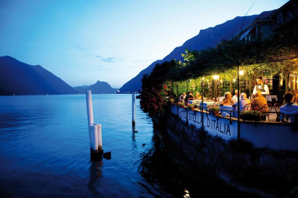 un gruppo di persone seduti in un bar sull'acqua di Hotel Stella D'Italia a Valsolda