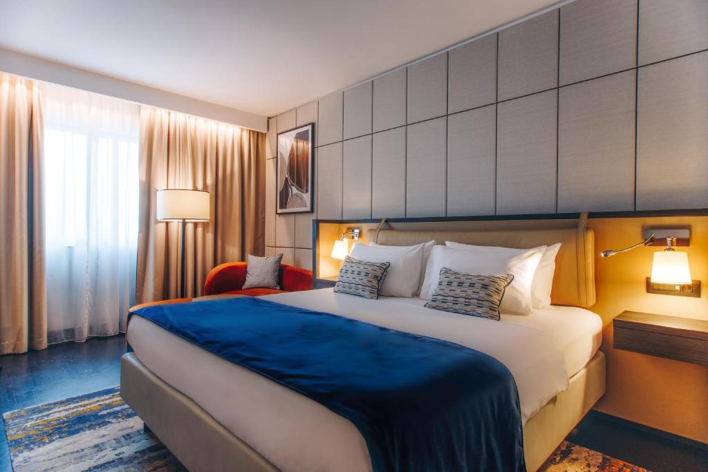 una camera d'albergo con un grande letto con una coperta blu di Crowne Plaza Belgrade, an IHG Hotel a Belgrado
