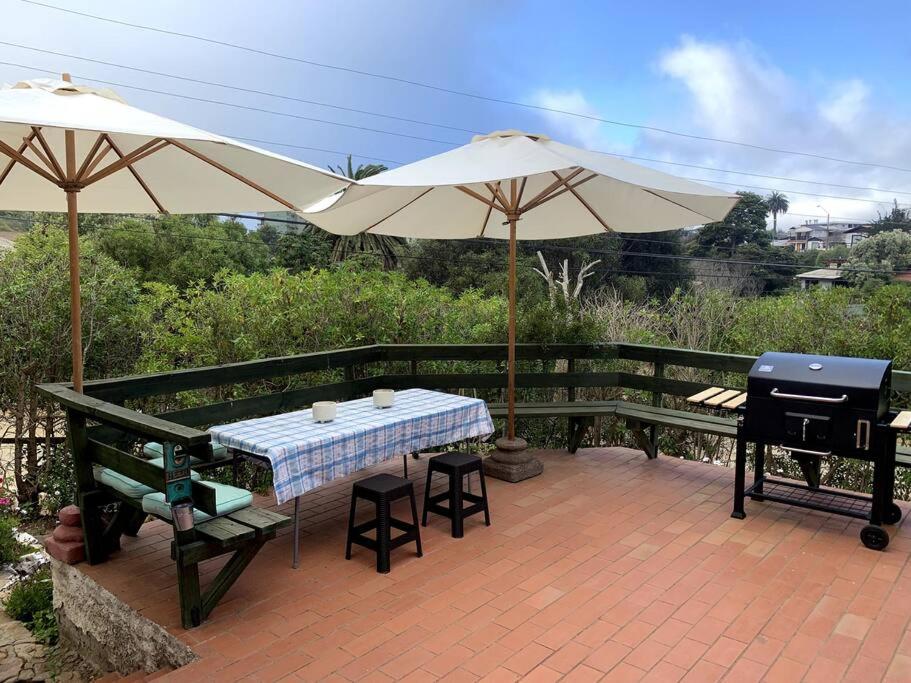 a patio with a table and an umbrella and a grill at Agradable y Acogedora casa de playa in Papudo