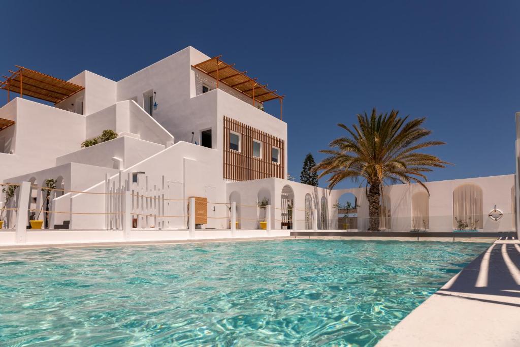 una villa con piscina di fronte a un edificio di Piccole Case a Kamari