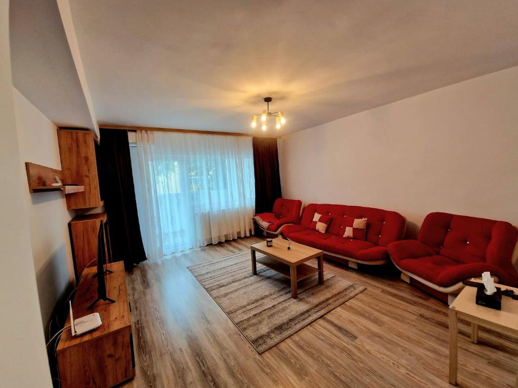 トゥルゴヴィシュテにあるMaribelle Appartmentsのリビングルーム(赤いソファ、テーブル付)