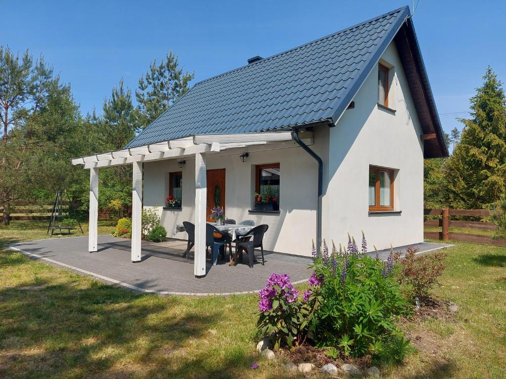 Cette petite maison blanche dispose d'une terrasse et d'une table. dans l'établissement Domek u Beti, à Wąglikowice