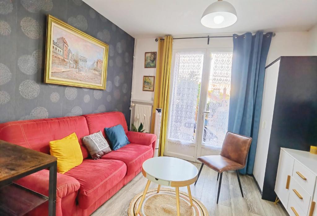 ein Wohnzimmer mit einem roten Sofa und einem Tisch in der Unterkunft Comfortable house 20 min to Paris with garden and BBQ in Épinay-sur-Orge