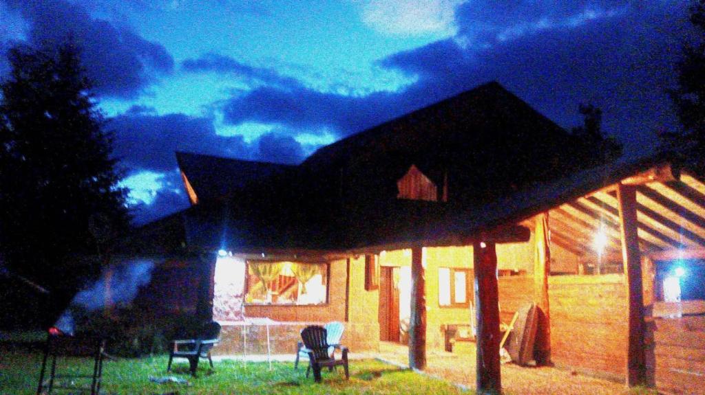 una casa con sedie seduta fuori di essa di notte di Cabaña Las Alpinas a Villa La Angostura