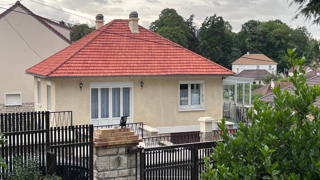 une maison avec un toit orange avec une clôture noire dans l'établissement Maison dans un endroit calme, à Saint-Leu-la-Forêt