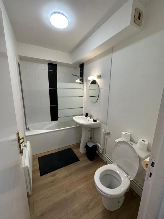 a white bathroom with a toilet and a sink at Le Jacquard in Calais