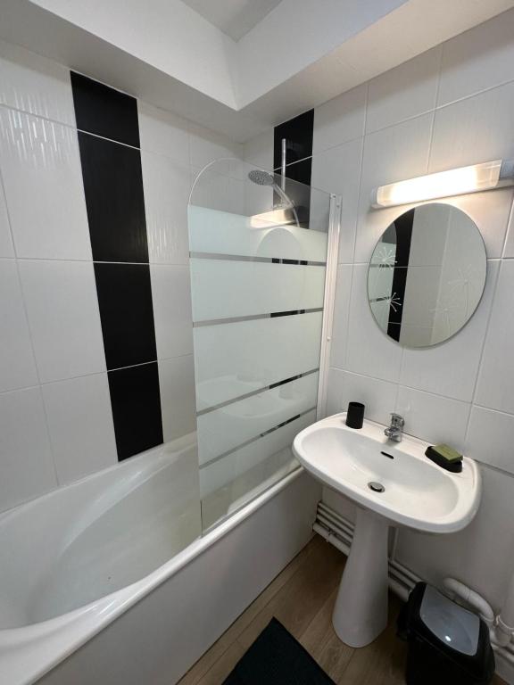 a bathroom with a sink and a mirror and a tub at Le Jacquard in Calais