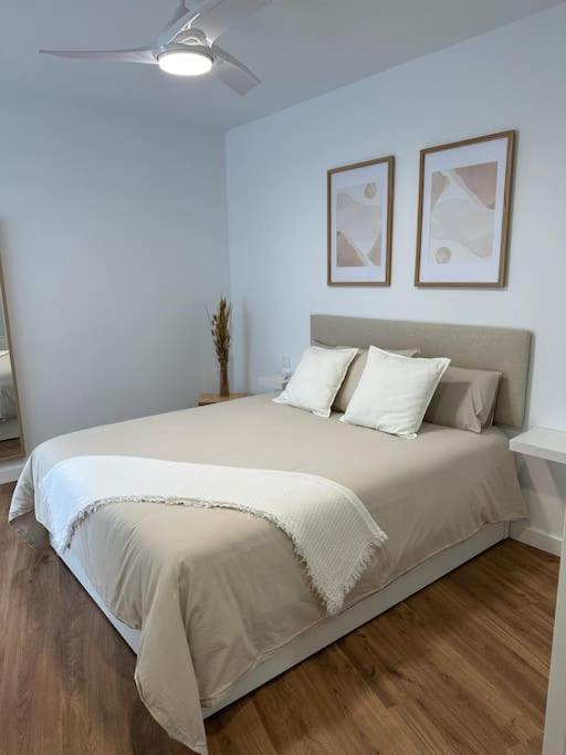 1 dormitorio con 1 cama grande con sábanas y almohadas blancas en Piso Comediantes, en Albelda de Iregua