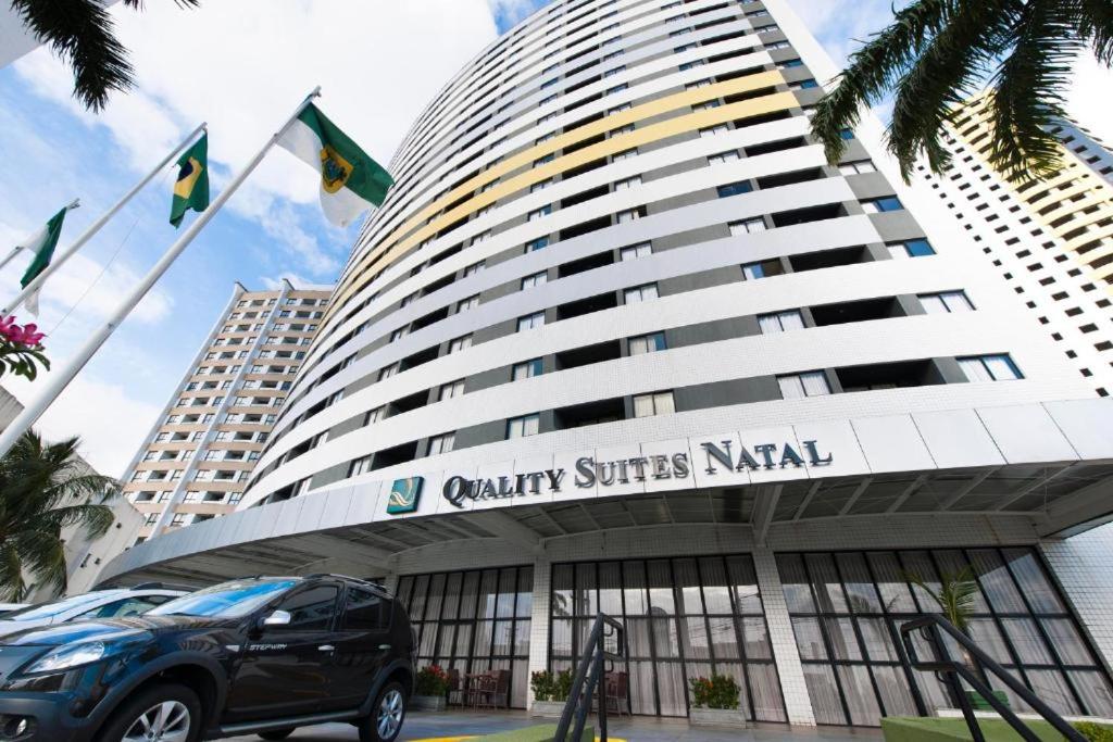 une voiture garée devant un grand bâtiment dans l'établissement Plaza Suítes Natal, à Natal