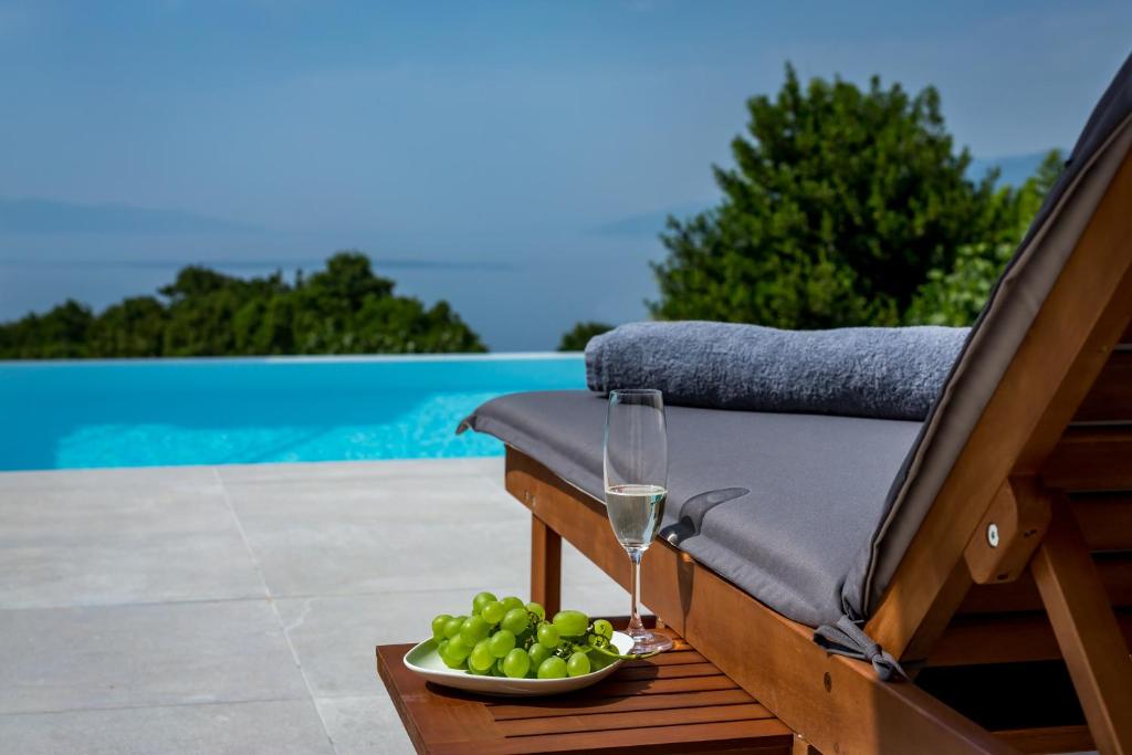 a glass of wine and a bowl of grapes on a chair at Vortex apartments, Opatija Riviera in Matulji