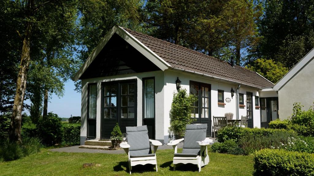 ein Haus mit zwei Stühlen und einem Tisch im Hof in der Unterkunft B&B Droom 44 in Buinerveen