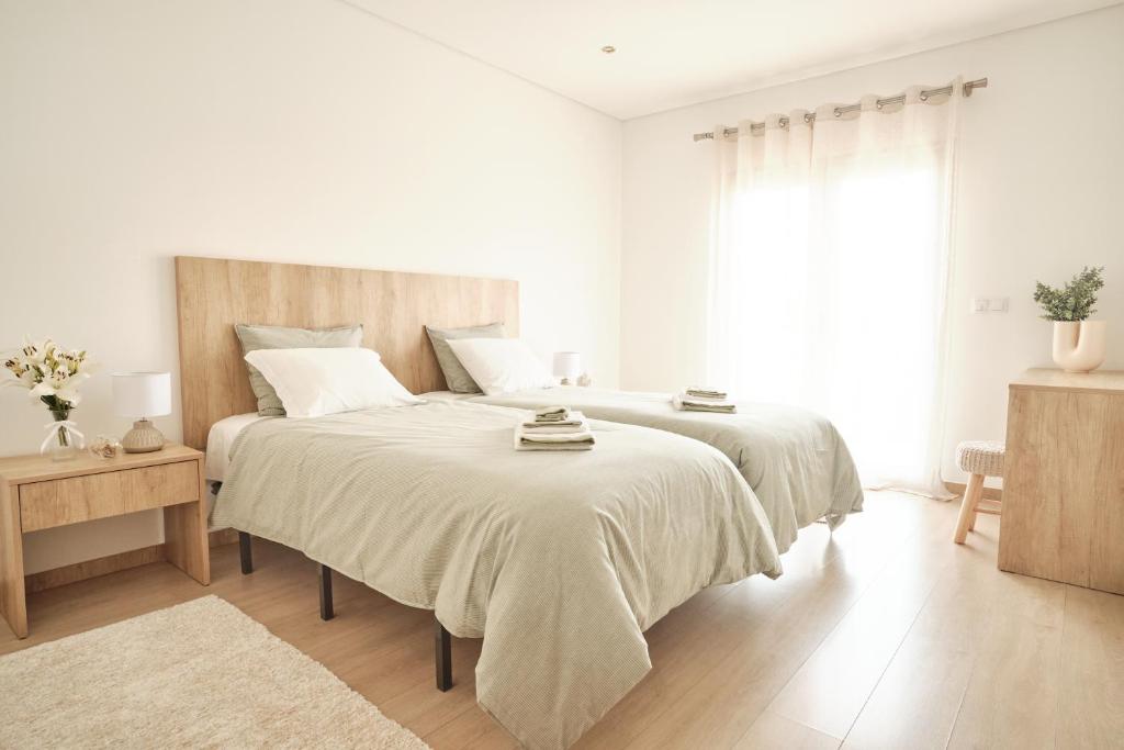 a white bedroom with a large bed and a window at CASA DO LÍRIO - Alojamento Local in Fátima