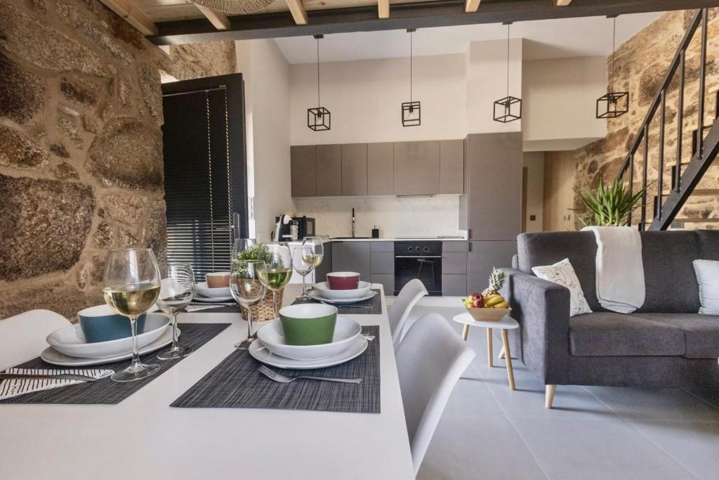 eine Küche und ein Wohnzimmer mit einem Tisch und Weingläsern in der Unterkunft Casa Entrehorreos in Carnota