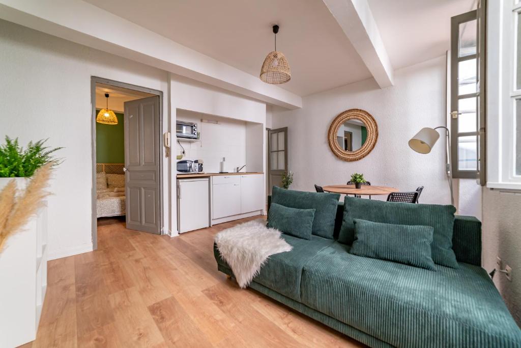 un salon avec un canapé vert et une cuisine dans l'établissement Centre ville - Proche des Arènes et de la Maison Carrée, à Nîmes