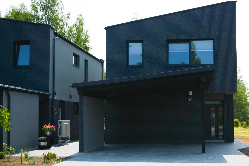 a black brick house with a garage at Koala rest house in Druskininkai