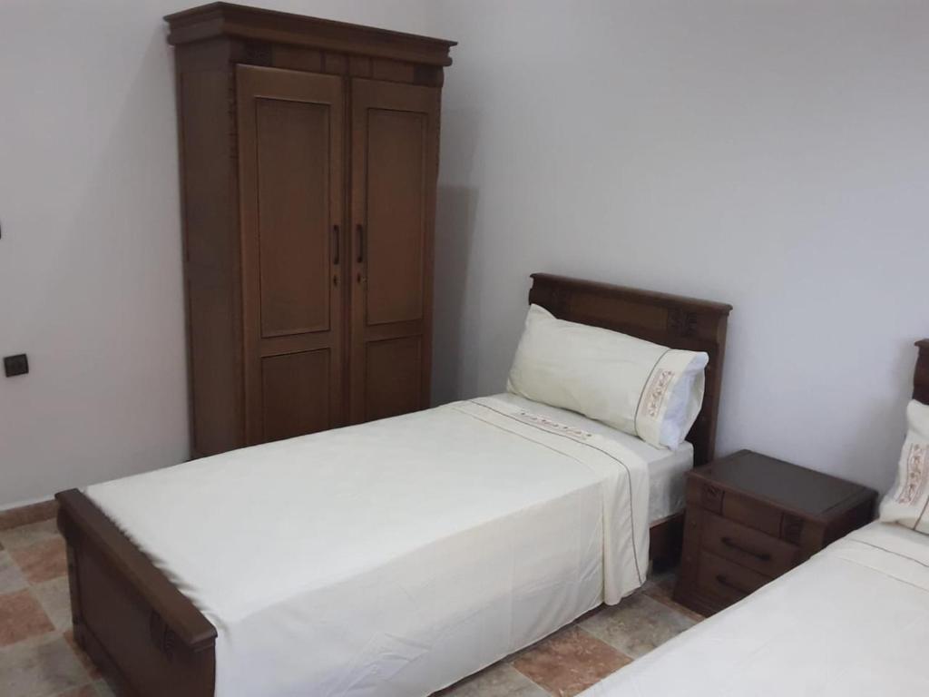 a bedroom with two beds and a cabinet at Coopérative Village Jbel Moussa du Tourisme in Rcham
