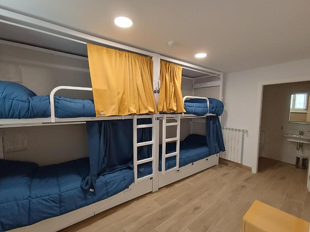 ein Zimmer mit zwei Etagenbetten mit blauen Sitzen in der Unterkunft Albergue SP 55 by Bossh! Hotels in Santiago de Compostela