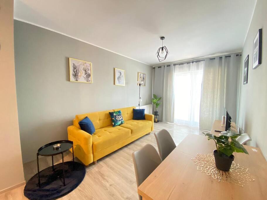 a living room with a yellow couch and a table at Vetulaniego Canary Comfort Apartment in Kraków