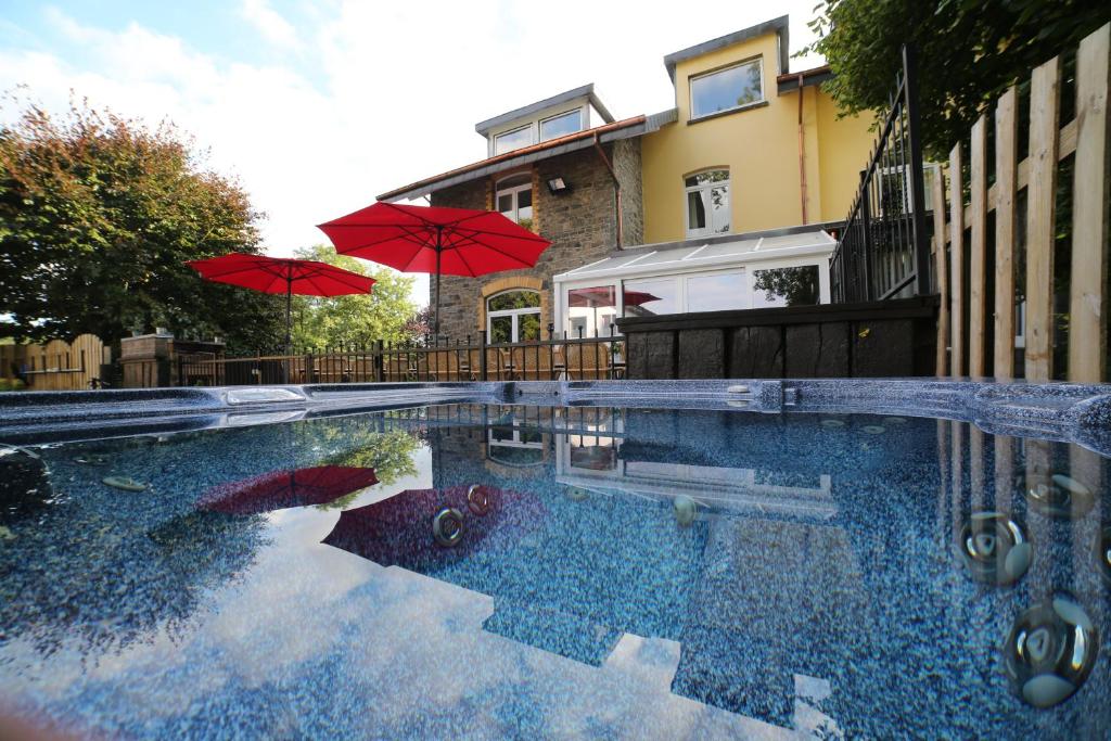 a swimming pool with two umbrellas and a house at Dolce Villa Pool and Wellness in Francorchamps