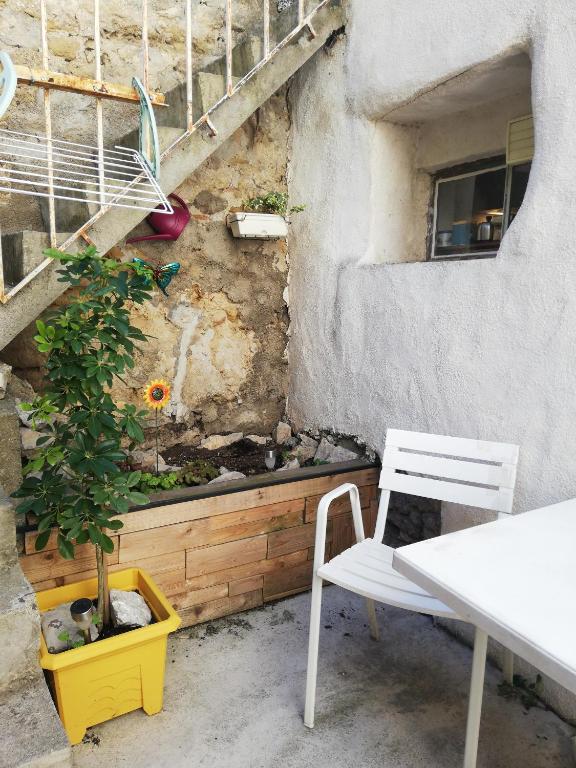 une table, deux chaises et une plante sur un mur dans l'établissement Charmant appartement en centre-ville médiéval, à Gigean