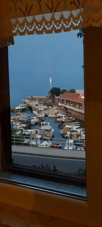une fenêtre avec vue sur un port de plaisance avec des bateaux dans l'établissement Apartman Cergolj, à Lovran