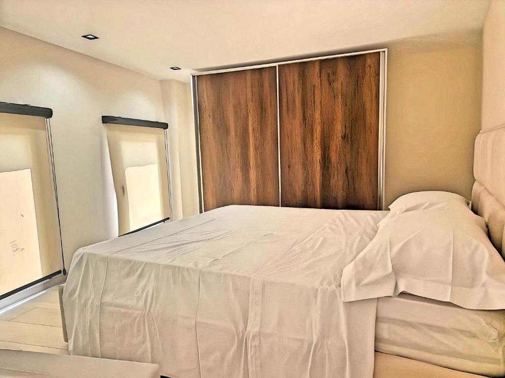 a bedroom with a large white bed with a wooden door at Suloti House Lungomare in Vlorë