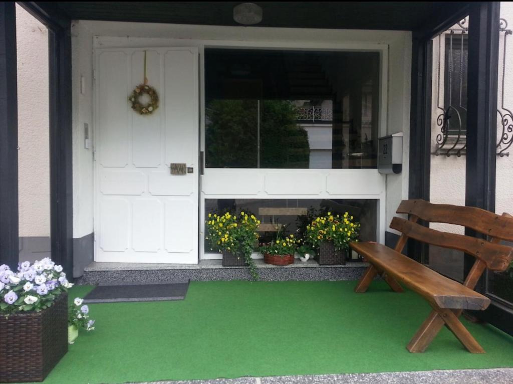 a porch with a bench and a door with flowers at Ferienwohnung & Zimmer in Olpe