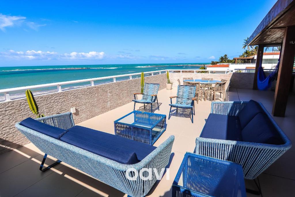 a patio with chairs and tables and the beach at Cobertura de Luxo em Resort Beira Mar - Qavi in Búzios