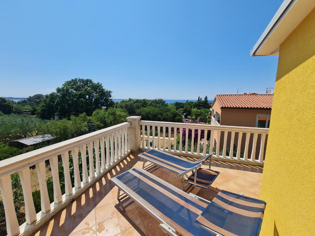 two blue chairs and a deckchair on a balcony at Apartments KUĆA SUNCE in Vodnjan