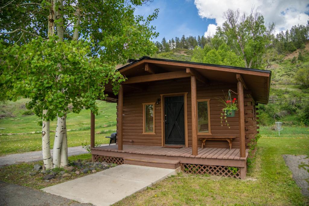 a small wooden cabin with a porch in the grass at High Creek Lodge and Cabins in Pagosa Springs
