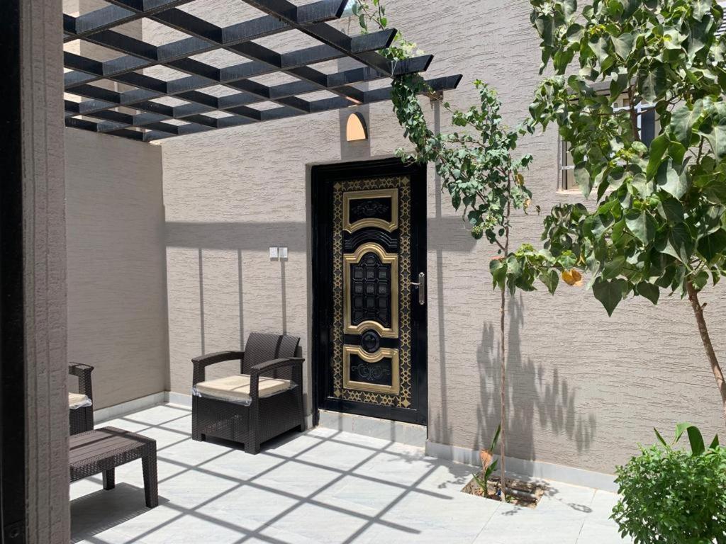 a patio with a black and gold door and a chair at شاليهات ليالي العقيق in Al Aqiq