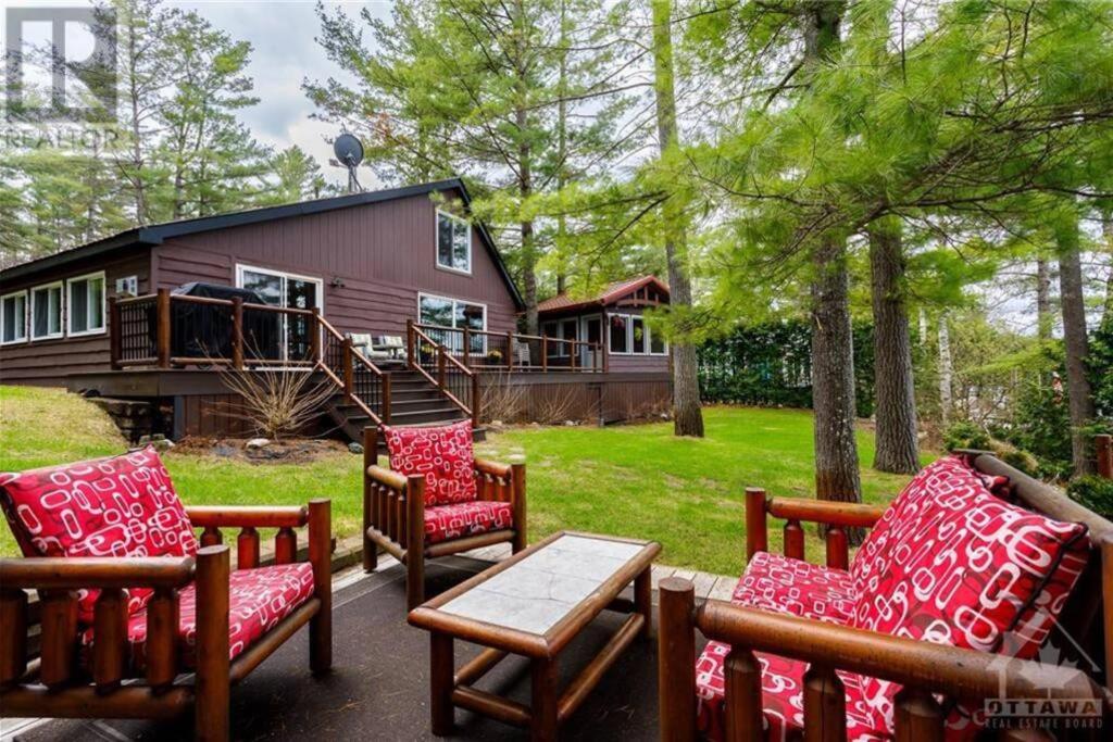 a group of chairs and a table in front of a house at Macwan's Lakefront Cottage in Calabogie