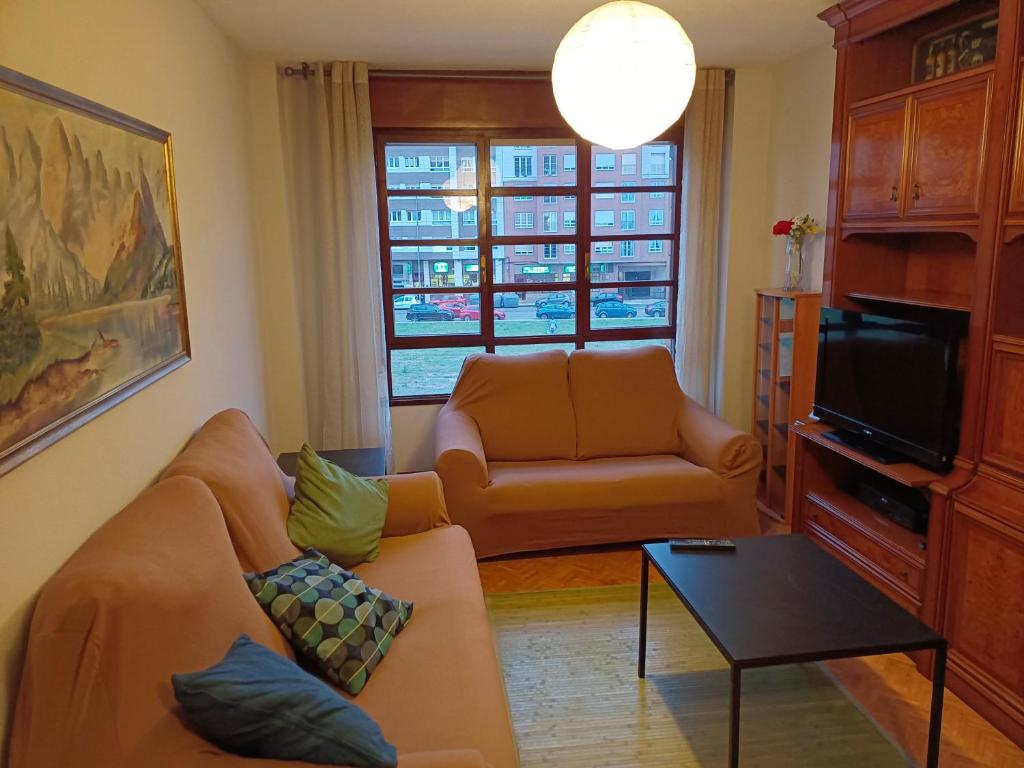 a living room with a couch and a tv at PONIENTE in Gijón