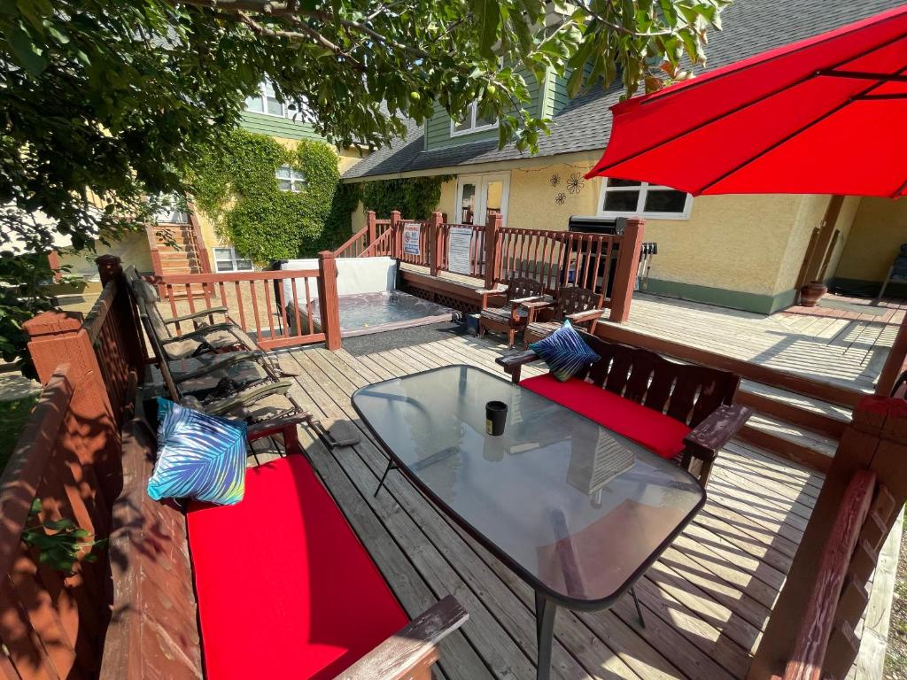 uma mesa e bancos num deque com um guarda-chuva vermelho em Blaeberry Valley Vacation Rentals em Golden