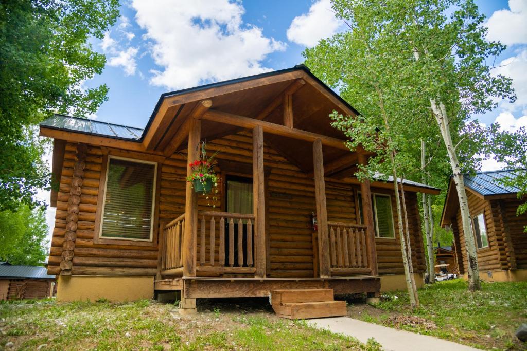 a log cabin with a porch and a house at High Creek Lodge and Cabins in Pagosa Springs
