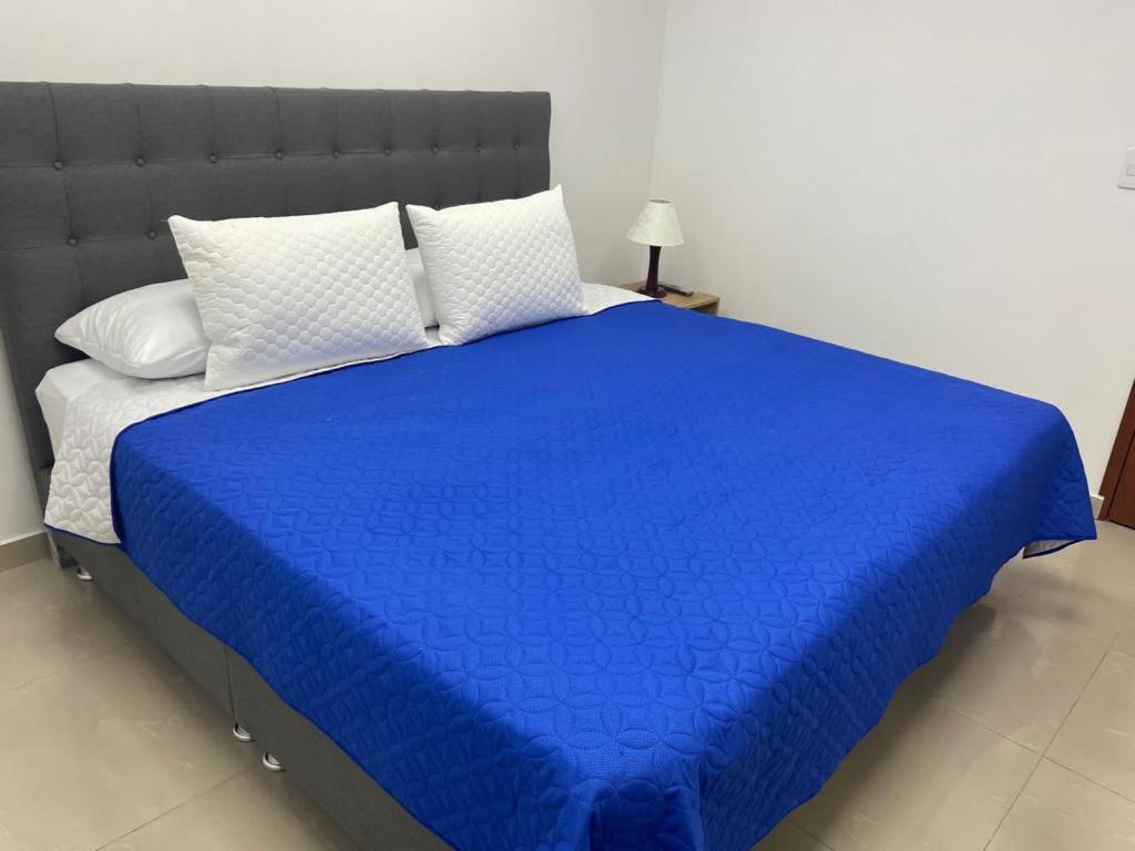 1 cama con manta azul y almohadas blancas en Aparta Hotel Montealegre en Bogotá