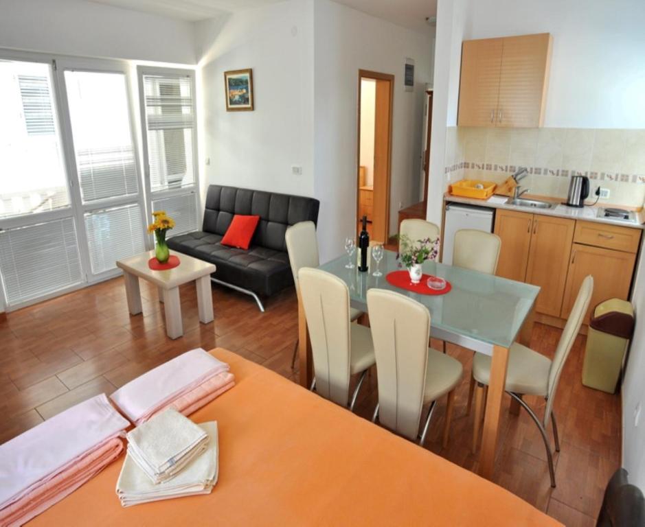 eine Küche und ein Wohnzimmer mit einem Tisch und einem Sofa in der Unterkunft Apartments Franićević in Petrovac na Moru