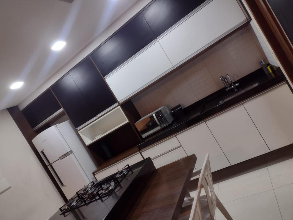 uma cozinha com armários a preto e branco e uma mesa de madeira em Casa na Serra. Negócios ou lazer em Serra