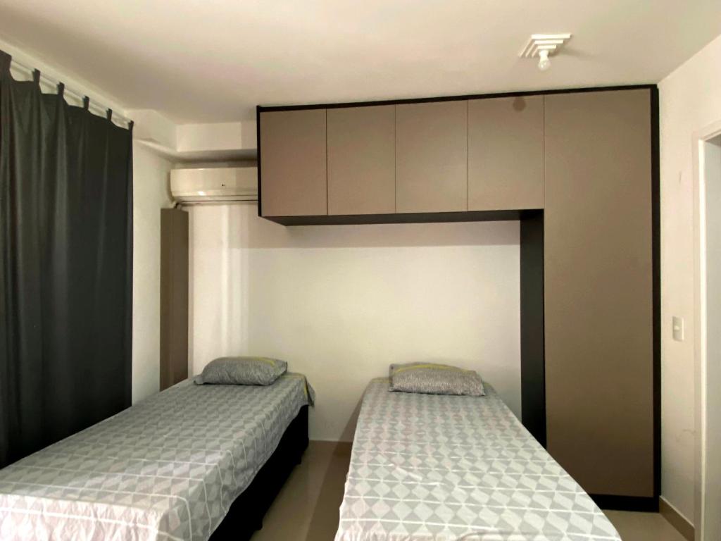 a bedroom with two beds and a cabinet at Studio APaulistana56 in Sao Paulo