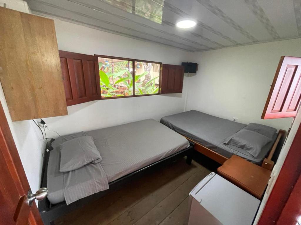 Habitación pequeña con 2 camas y ventana en Cabañas las perlas, en Bahía Solano