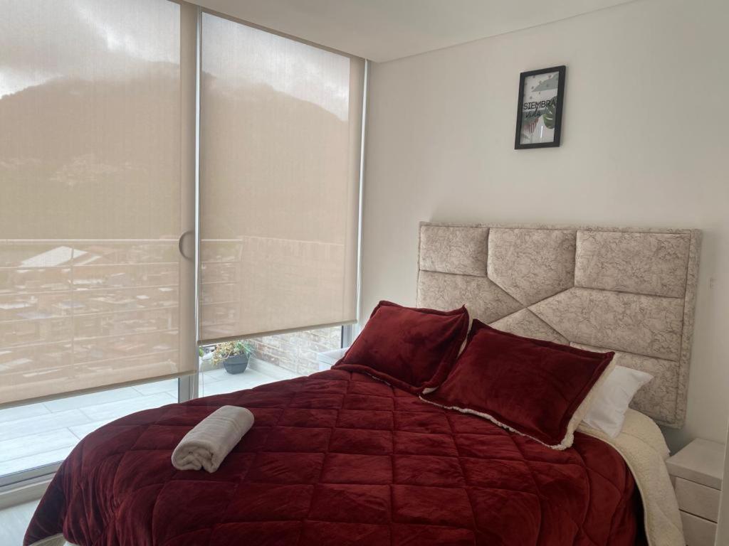 um quarto com uma cama grande, cobertores vermelhos e almofadas em Centro Internacional - La Quinta em Bogotá