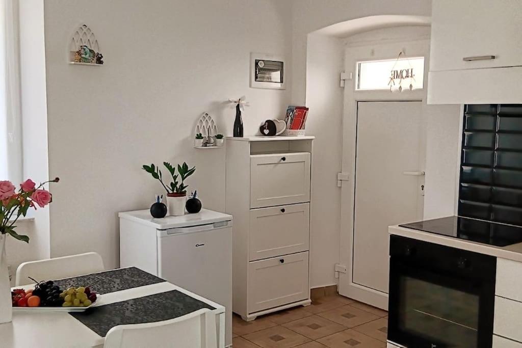 una cucina con mobili bianchi e tavolo di Lovely apartment Morje - Koper old town a Capodistria